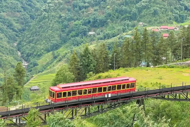 Red mountain train in Sapa, crossing lush valleys and offering breathtaking views of the Muong Hoa landscape.